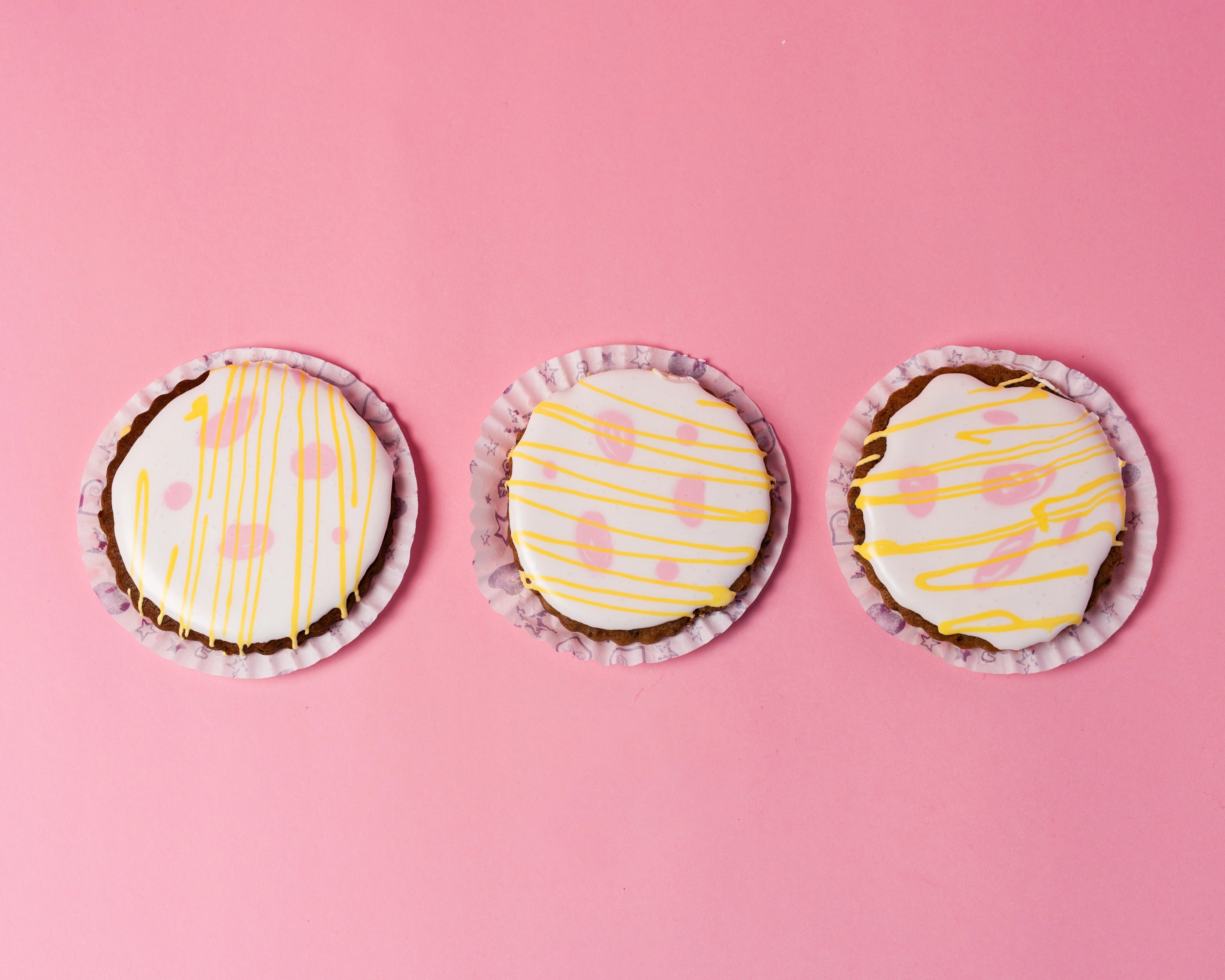 easter cookies bundle with white icing and yellow drizzle on chocolate base arranged on pink background, red ribbon cakes & bistro dubai